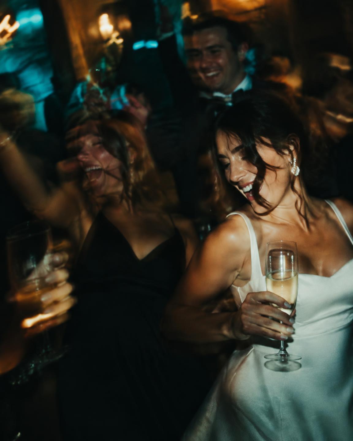 Bride laughing with champagne on the dance floor